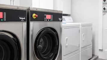 A laundry room with two front-loading washing machines and a dryer.
