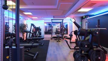 A gym with various exercise equipment, including dumbbells, a bench, and a squat rack.
