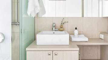 Un baño moderno con cabina de ducha de vidrio, un lavabo blanco y un mueble de madera.