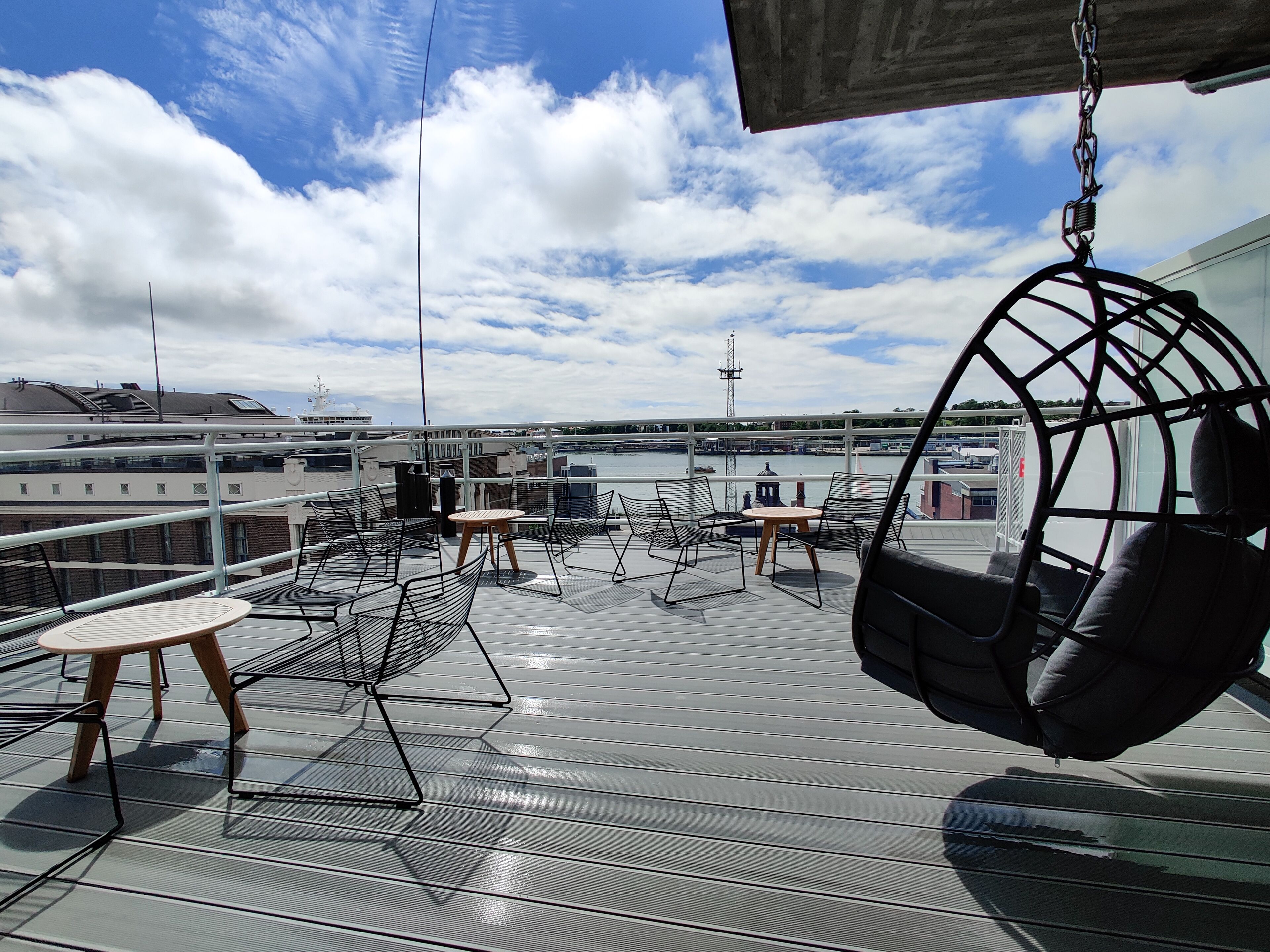 Eine Dachterrasse mit Metallstühlen, einer Schaukel und einem kleinen Tisch.