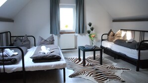 Un dormitori tipus loft amb dos llits superposats, una catifa amb dibuixos de zebra i una taula petita amb un ram.