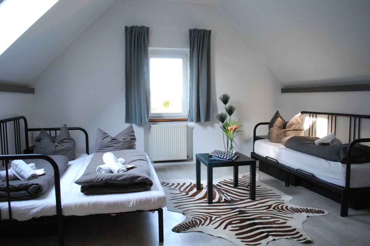 A loft bedroom with two bunk beds, a zebra-patterned rug, and a small table with a vase.