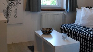 Habitació amb finestra, radiador, taulell blanc amb un bol i un got, sofà estampat i una obra d'art amb un esquelet de zebra a la paret.