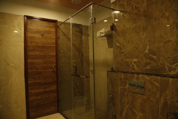 A glass-enclosed shower with a wooden door, marble walls, and a towel rack. - Hotel New York Plaza (Una)