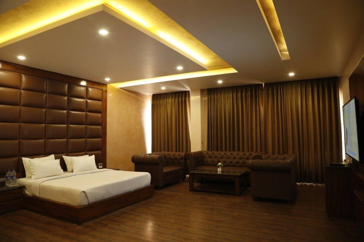 Ein Hotelzimmer mit einem großen Bett, zwei Sofas, einem Couchtisch und einem Fernseher.