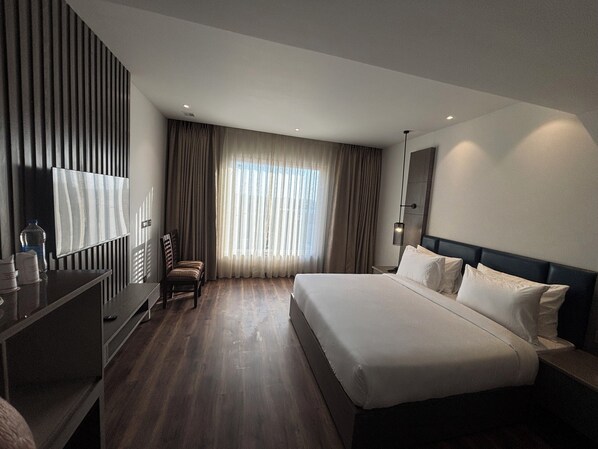 A modern hotel room with a large bed, a desk, a chair, and a TV. - Hotel New York Plaza (Una)