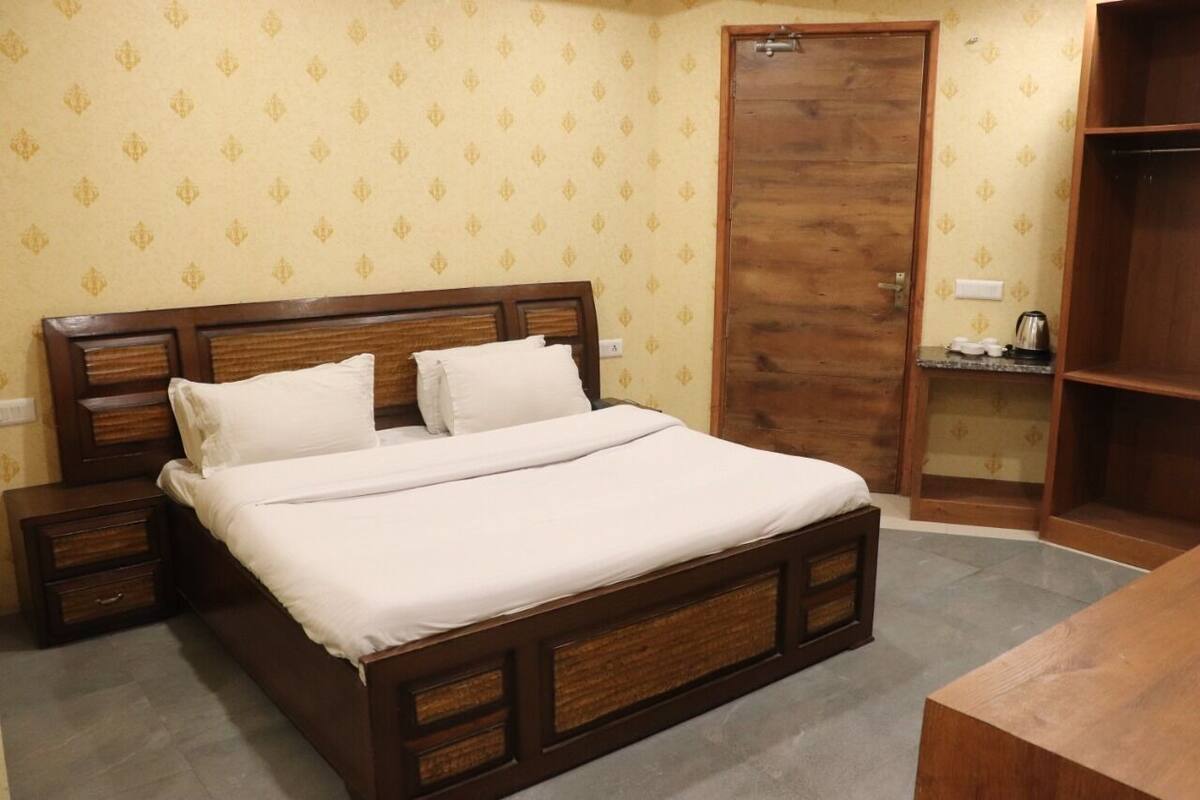 Ein ordentlich bezogenes Bett mit Holzabdeckung, ein Nachttisch und ein Schrank mit Spiegel.