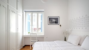 A bedroom with a large bed, a window with blinds, a chair, and a wardrobe. - Art in Athens Suite (Athens)