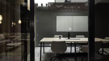 Una sala conferenze moderna con pareti divisorie in vetro, un tavolo grande e diverse sedie.