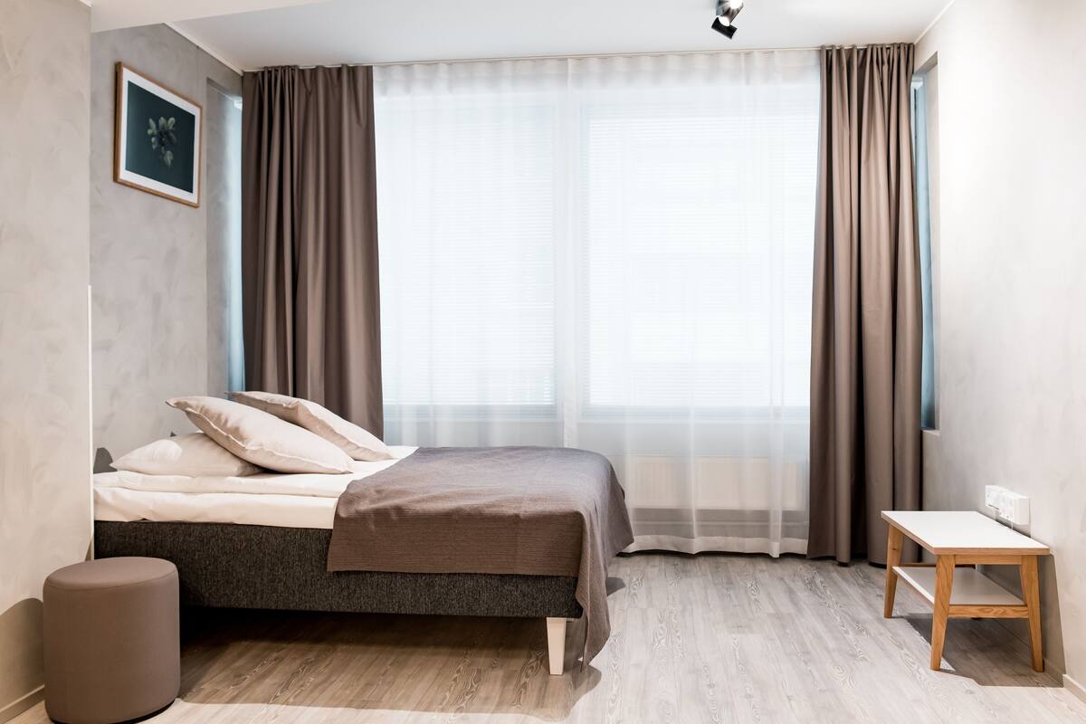 Une chambre moderne avec un lit, une table de chevet et une fenêtre avec des rideaux.