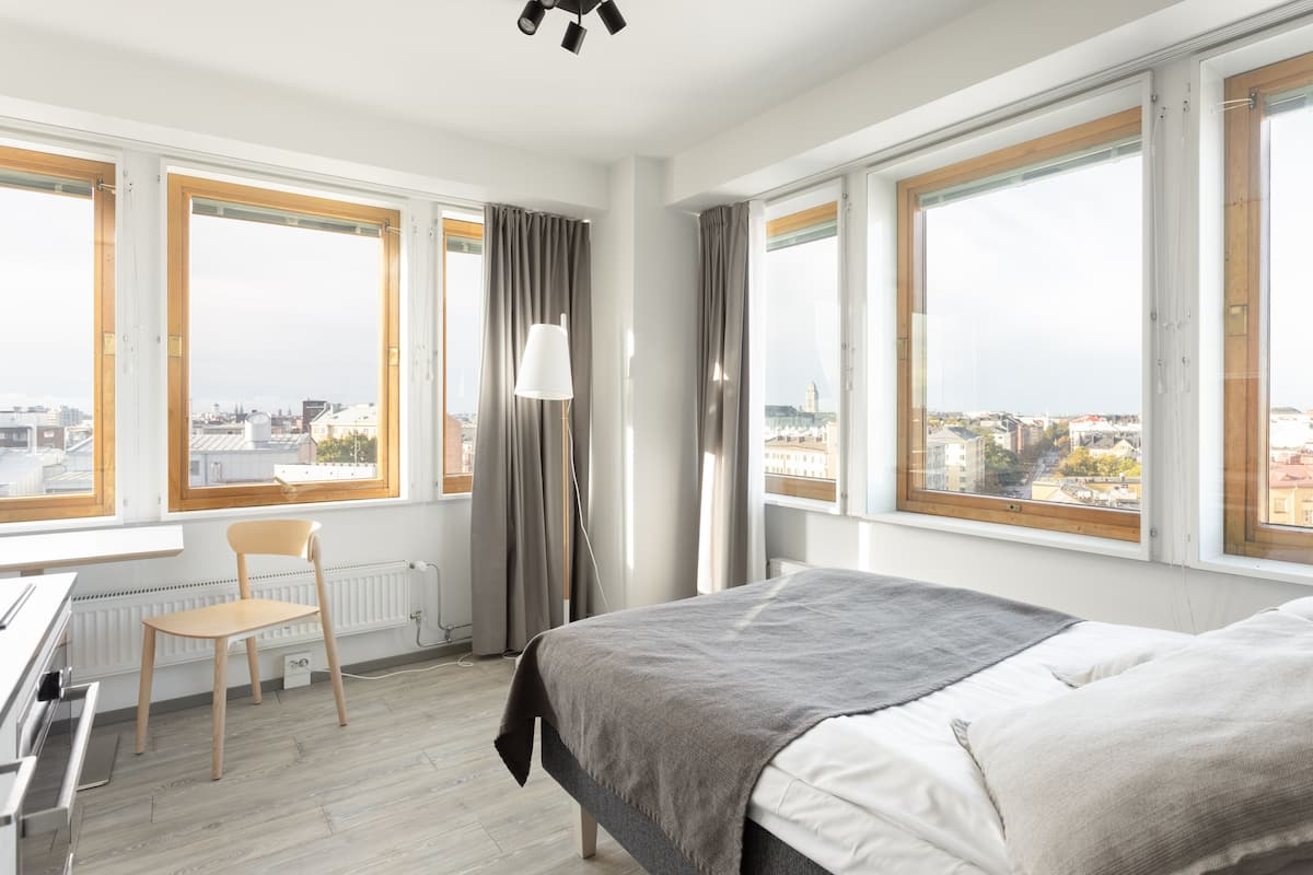 Une chambre d’hôtel moderne dotée de grandes fenêtres, d’un lit, d’un bureau et d’une chaise.