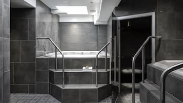 Relax in a serene bathroom with a bathtub and sleek, dark tile flooring.