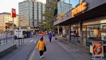 A city street with a pedestrian crossing, a bus, and a building with a 'picnic' sign.