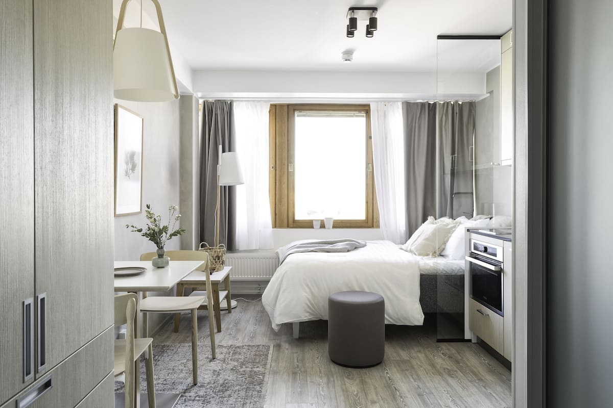 Une chambre moderne avec un lit, une table de chevet et une petite kitchenette.