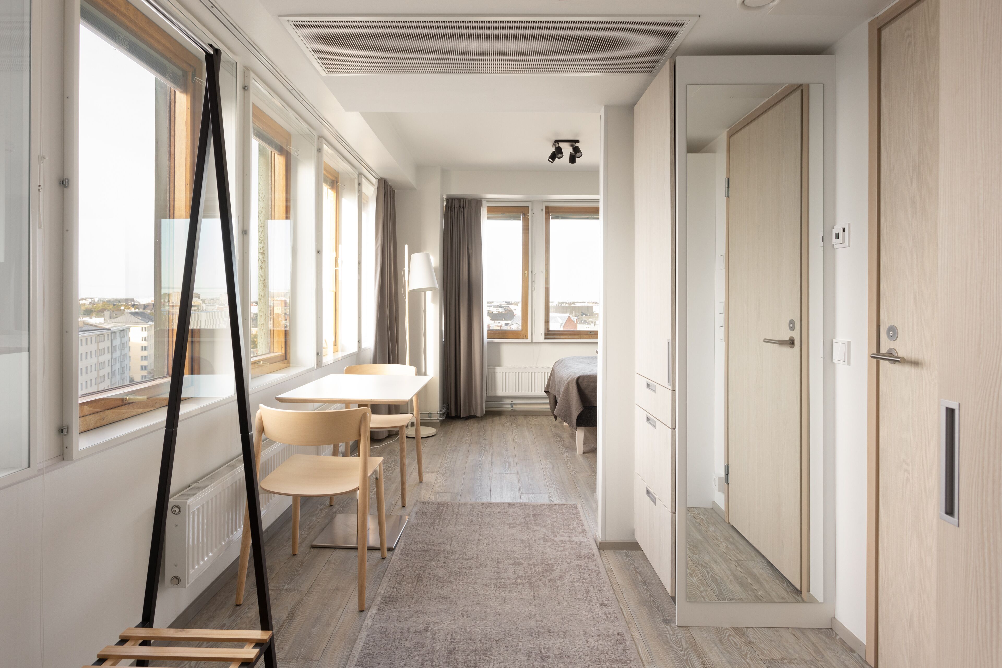 Een moderne hotelkamer met een groot raam, een bed, een bureau en een kledingkast.