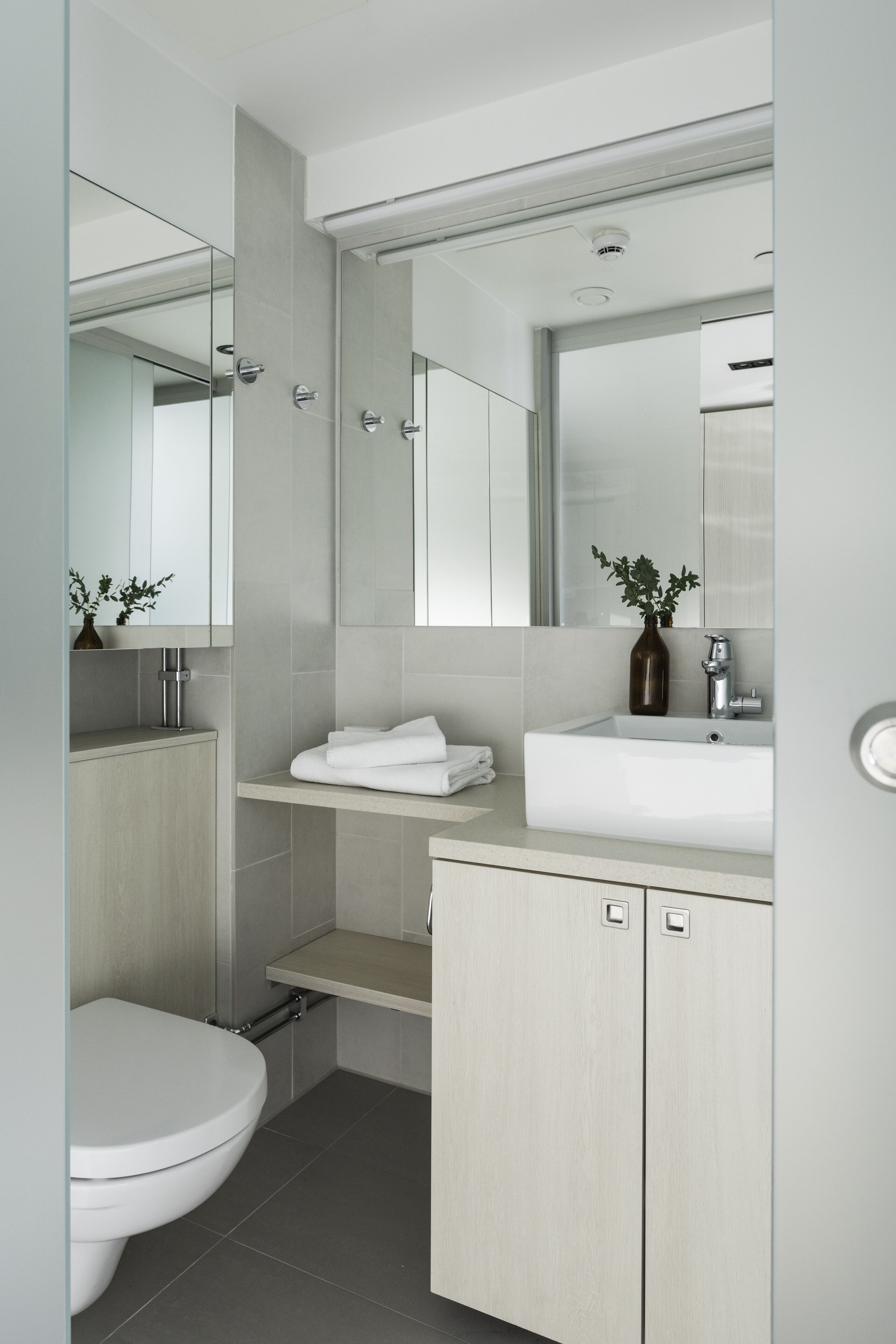 A modern bathroom with a toilet, sink, and mirror.