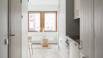 Eine moderne Küche mit Holzausstattung, einem Einbauofen und einem Fenster mit Blick auf Gebäude.