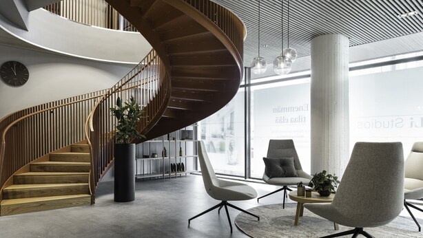 A modern interior with a spiral staircase, contemporary chairs, and a large window. - Noli Sörnäinen (Helsinki)