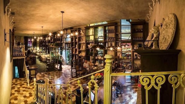 Un interior amplio con suelo a cuadros, barandillas ornamentales y varios estantes llenos de objetos.