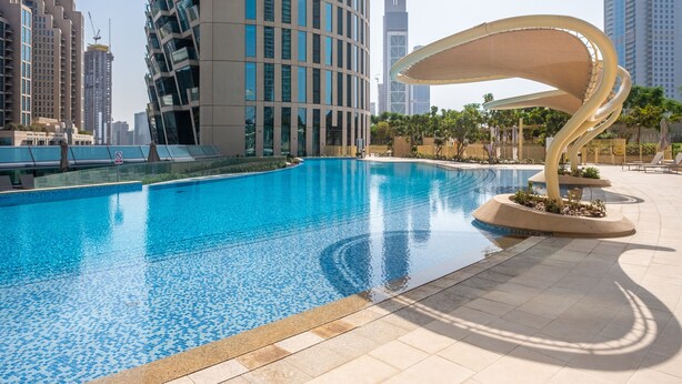 A modern swimming pool with a unique architectural feature, surrounded by high-rise buildings and a clear sky. - Bravo Way Burj Vista 1 (Dubai)