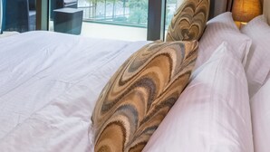 A hotel room with a large bed, a view of a city skyline through floor-to-ceiling windows, and a seating area with a table and chairs. - Bravo Way Burj Vista 1 (Dubai)