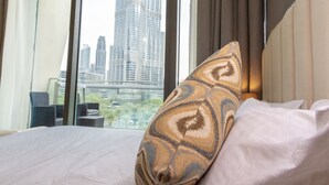 A hotel room with a bed, a patterned pillow, and a view of a cityscape through large windows. - Bravo Way Burj Vista 1 (Dubai)