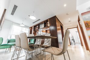 Ein moderner Essbereich mit einem Holztisch und -stühlen, einem grünen Sofa und einem großen Fenster, das natürliches Licht hereinlässt.