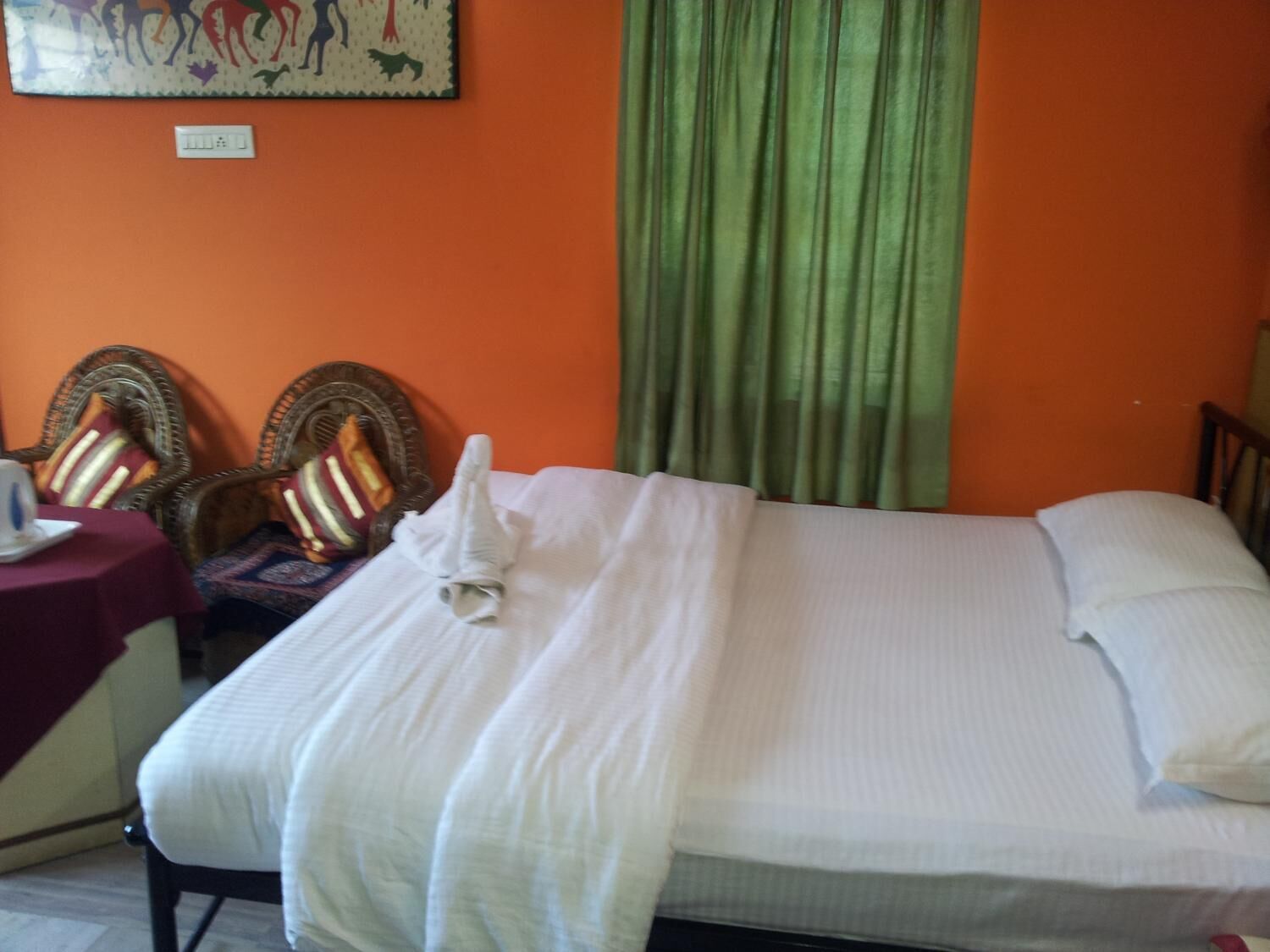A hotel room with a bed, a table with a chair, and a decorative wall piece.