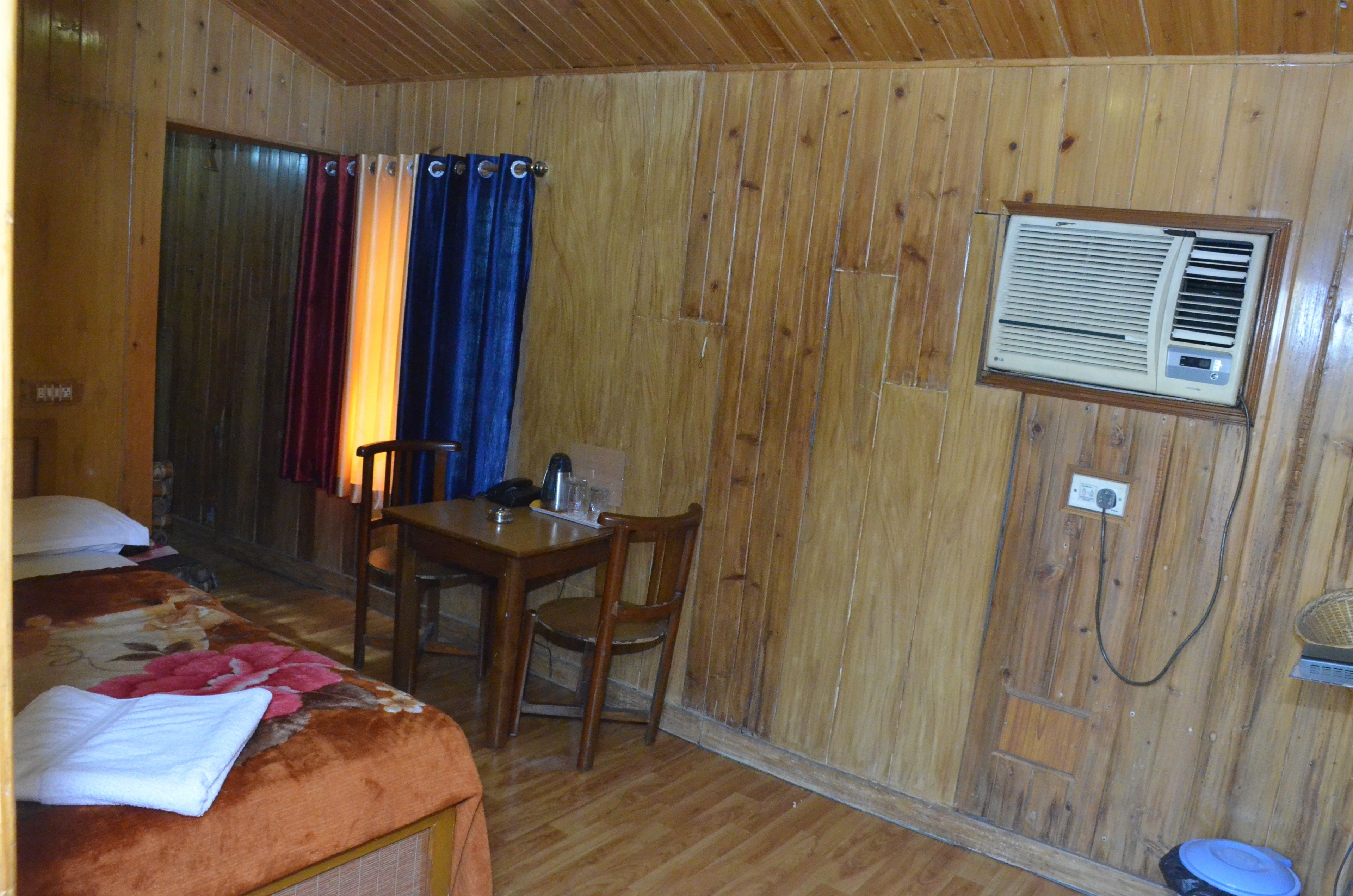 A wooden-paneled room with a bed, a table, and a chair.