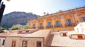 A building with a tiled roof and multiple windows, overlooking a mountainous area.