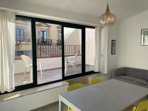 Quarto com varanda, mesa de jantar e sofá.