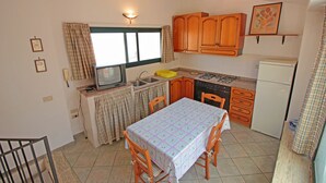 A compact kitchen with wooden cabinets, a dining table, and a small window.