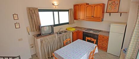 Una cocina compacta con armarios de madera, una mesa de comedor y un ventanal.