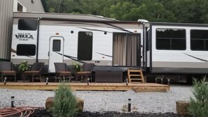 Ein Wohnmobil mit überdachter Terrasse, einer Schiebetür und einer kleinen Holzterrasse.