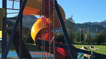 Un parque infantil con columpios, un tobogán y una estructura para escalar.