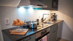 Una cocina moderna con electrodomésticos de acero inoxidable, una tabla de cortar de madera y un recipiente de vidrio para servir.