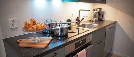 Una cocina moderna con electrodomésticos de acero inoxidable, una tabla de cortar de madera y un recipiente de vidrio para servir.