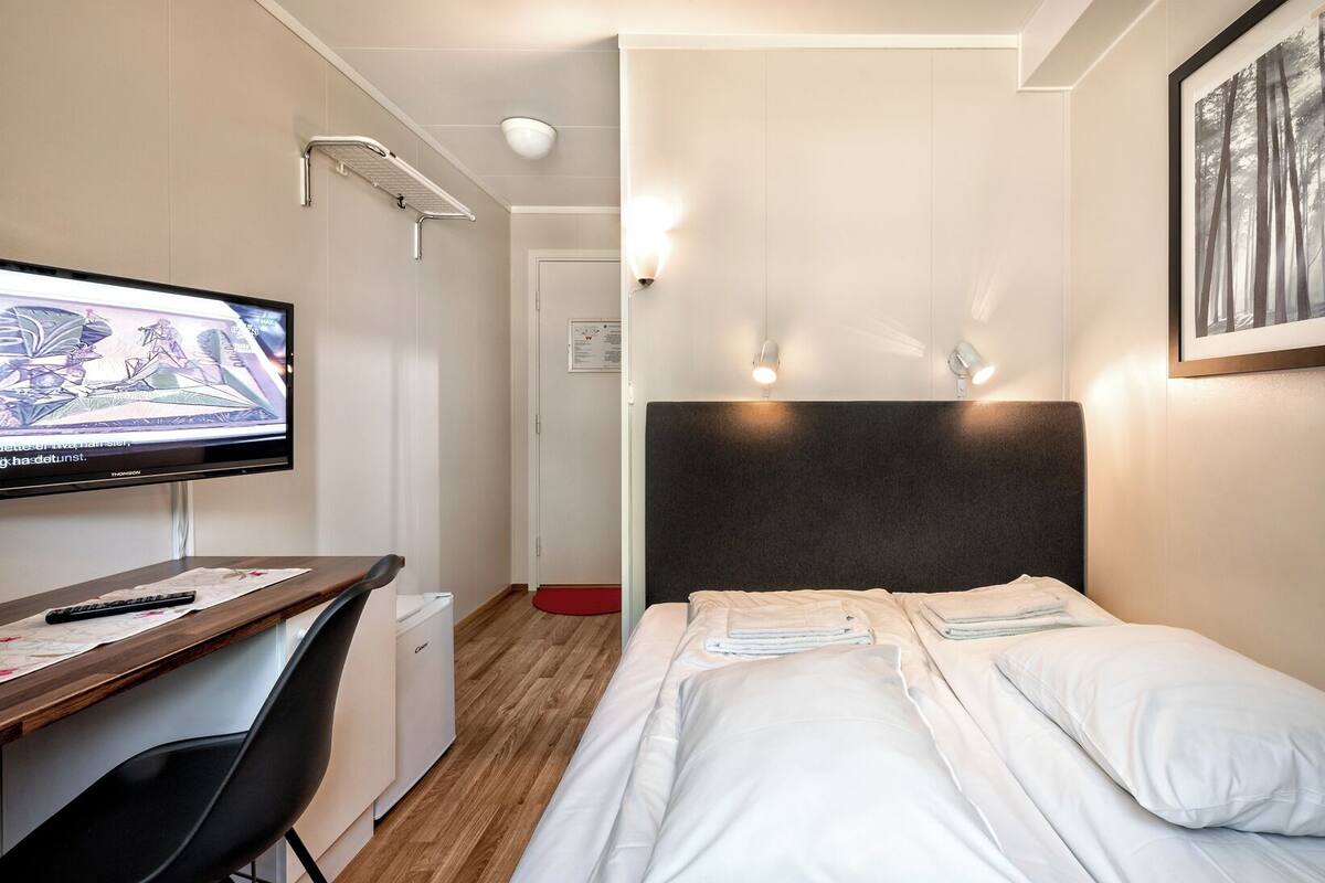 Ein Hotelzimmer mit Bett, Schreibtisch mit Computer, Fernseher und Duschbereich.