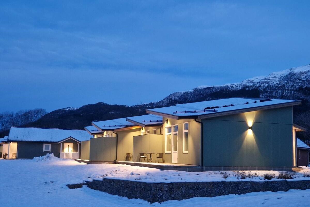 Ein modernes Haus mit überdachter Terrasse und einer Steinmauer.