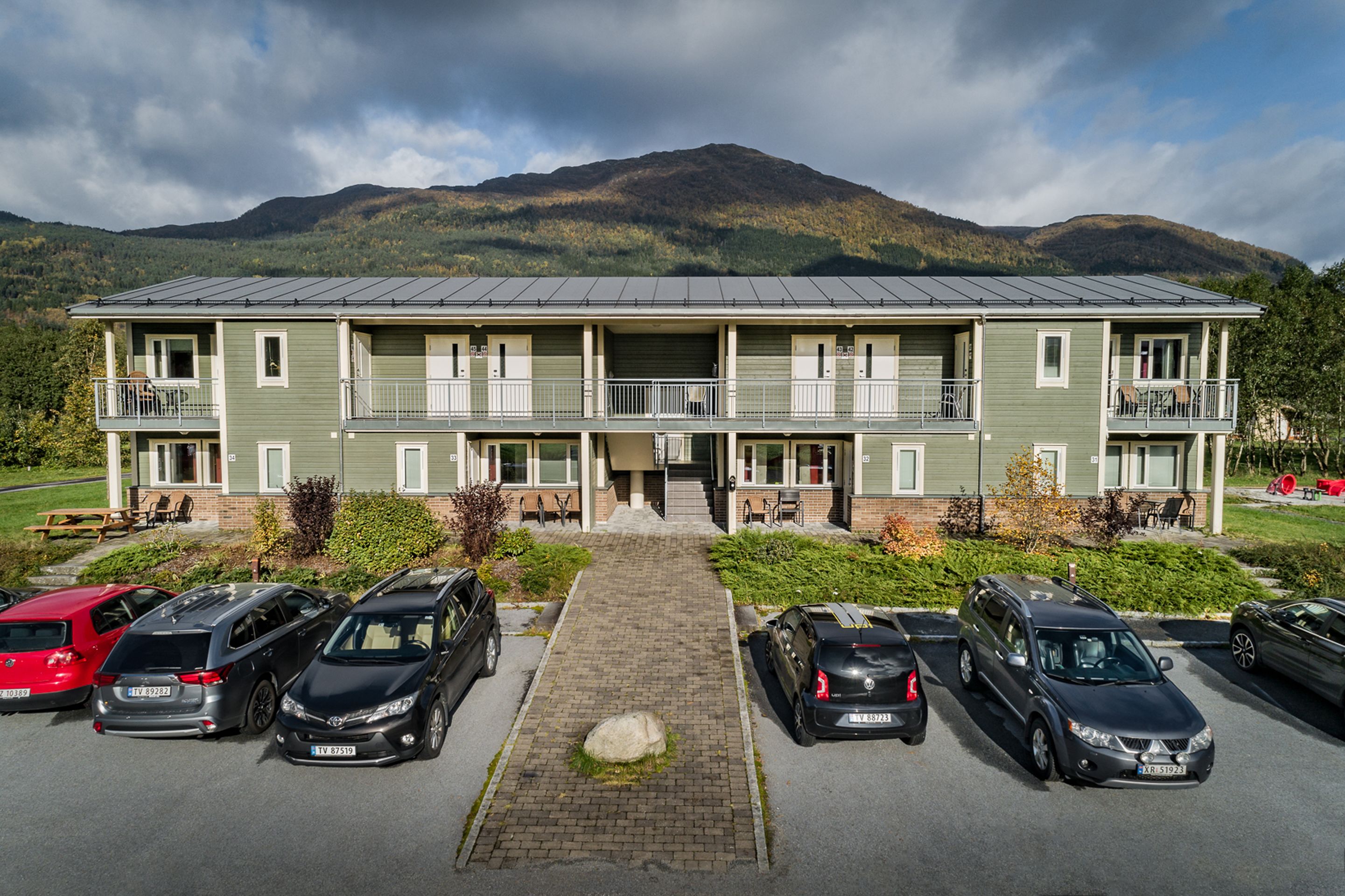 Un immeuble à plusieurs étages avec un parking situé devant.