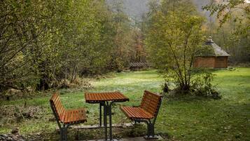 A wooden bench and table in a grassy area with a cabin in the background.