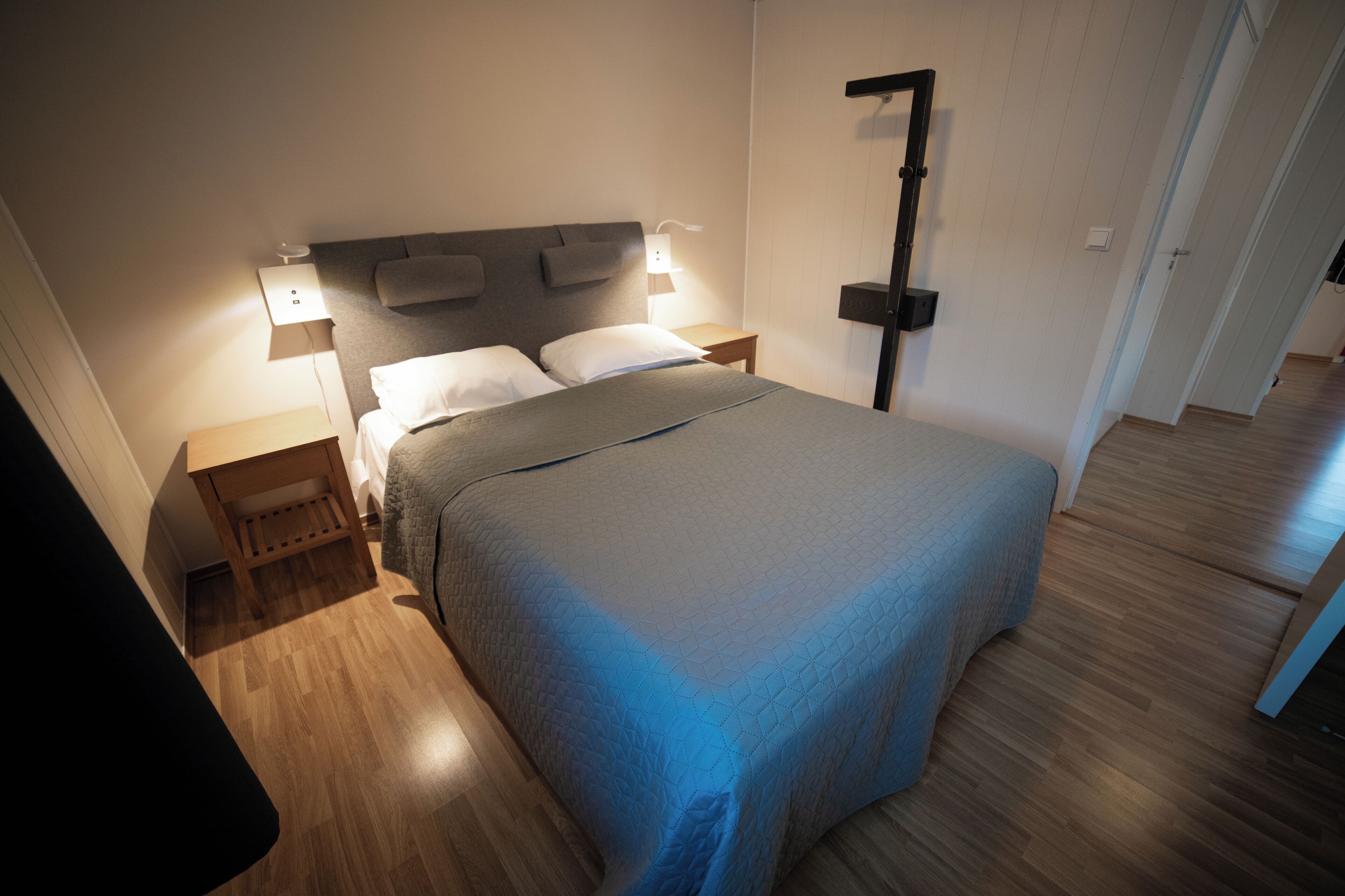 Un dormitorio moderno con una cama grande, mesitas de noche y una mesita auxiliar.