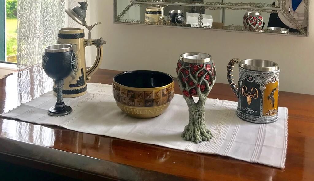 Een tafel met een wit kleed, een decoratieve boom, een schaal en twee mokken met gedetailleerde patronen.