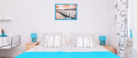 Quarto com cama, duas mesas de cabeceira, uma cadeira, um quadro na parede e janela com cortinas.