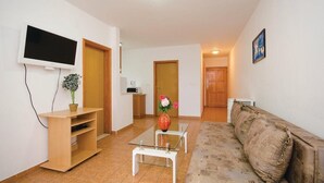 A living room with a TV, a coffee machine, a sofa, and a small table with a vase of flowers. - Apartments Ciovo (Okrug)