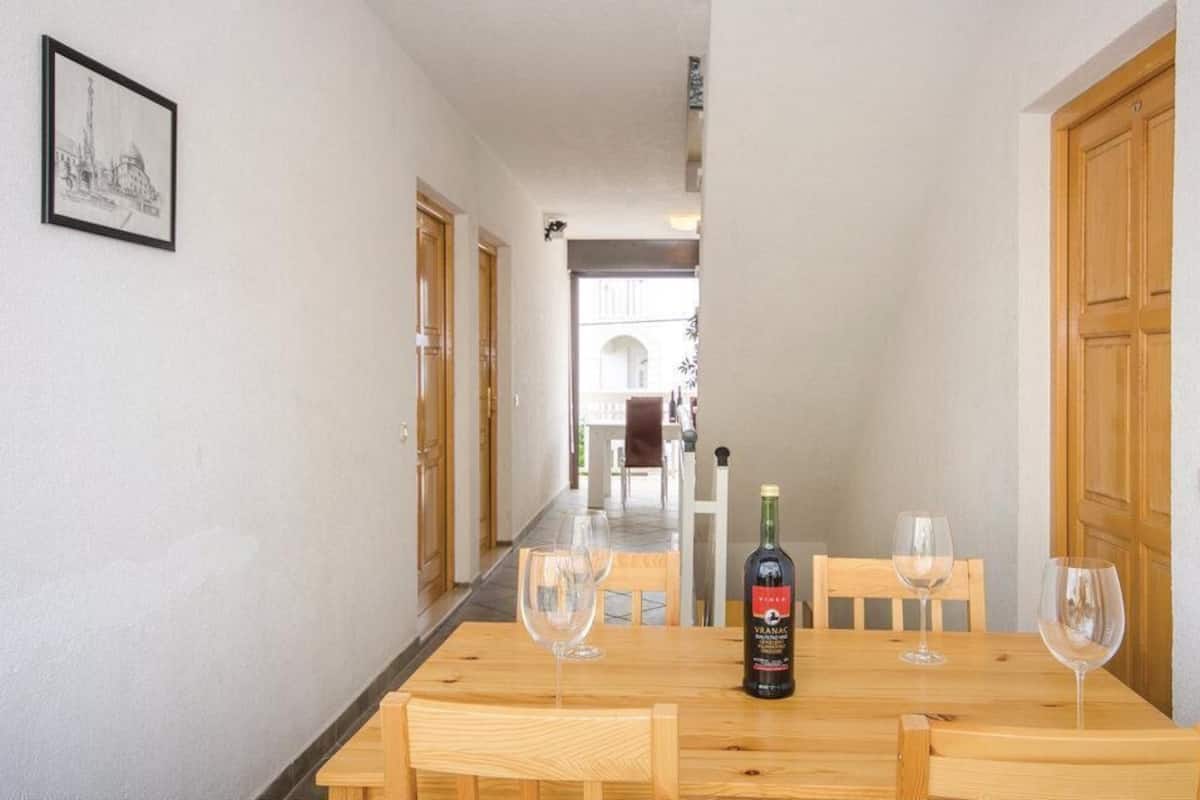 Uma sala de jantar com uma mesa de madeira, quatro cadeiras e uma garrafa de vinho.