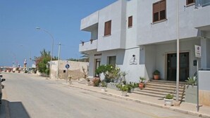Un edificio moderno con fachada plana, varias ventanas y una pequeña entrada con escalones.