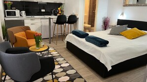 Habitación de hotel moderna con cama, sofá, kitchenette y baño.
