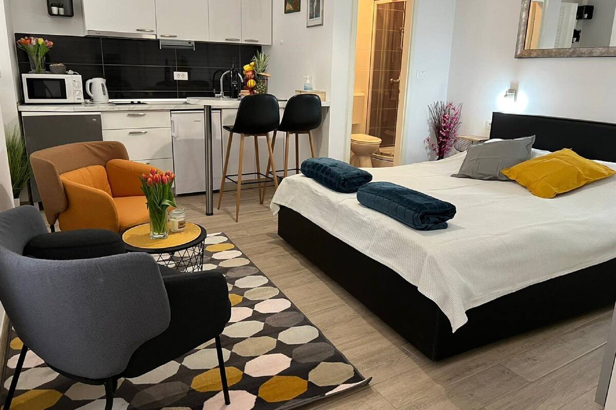 Et moderne hotelværelse med seng, sofa, tekøkken og badeværelse.