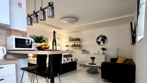 Una cocina moderna con comedor, un sofá negro y una pequeña mesita con una planta.